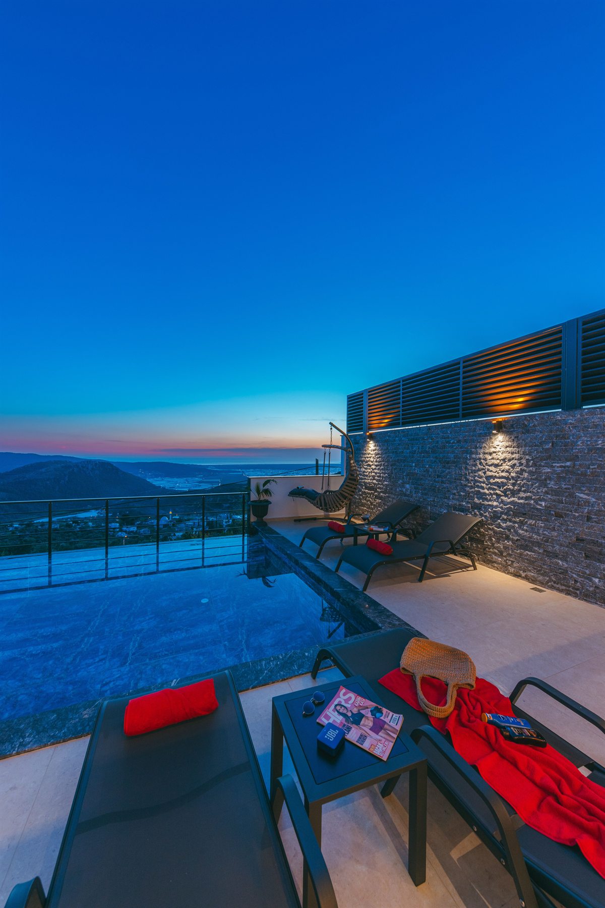 Evening pool terrace with red cushions and sea views